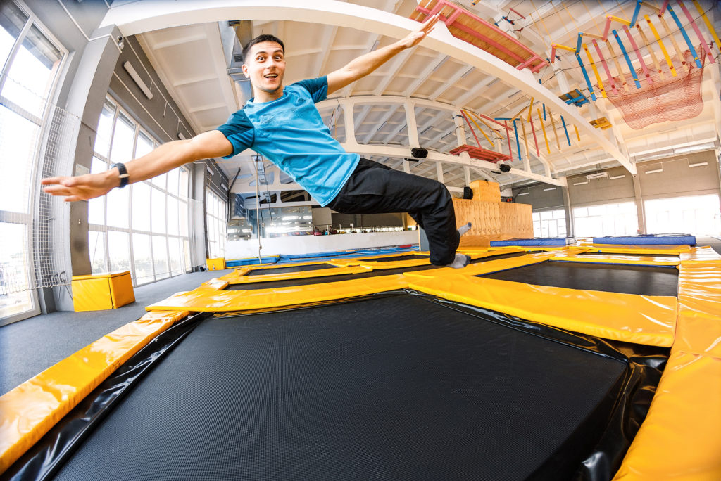 Happy emotional man jumping and flying in trampoline sport center indoors Happy emotional man jumping and flying in trampoline sport center indoors